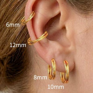 May include: Four gold-toned hoop earrings of varying sizes are displayed on an ear. The smallest hoop is labeled 6mm, the mid-sized hoop is 8mm, the larger hoop is 10mm, and the largest hoop is 12mm. Each earring features a simple, circular design.