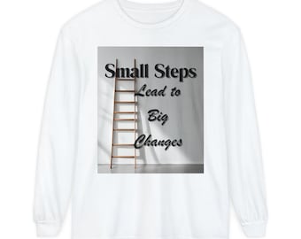May include: White long-sleeve shirt featuring the text "Small Steps Lead to Big Changes" with a wooden ladder graphic. The design is centered on the shirt, offering a motivational message. The shirt is made of a soft, comfortable material.