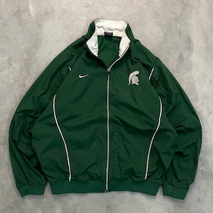 May include: A green zip-up jacket with white trim and a white collar. The jacket features a Nike logo on the chest and a Spartan helmet logo. The jacket is made of a lightweight material.