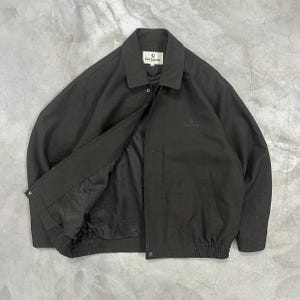 May include: A dark brown jacket with a button-up front, collar, and elasticized waist. The jacket has a logo on the chest and the brand name "Guy Laroche" on the label.