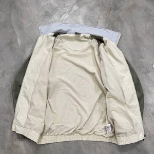 Peut inclure: Veste vert clair et cr&egrave;me avec un col bleu clair. La veste est ouverte, r&eacute;v&eacute;lant une doublure int&eacute;rieure cr&egrave;me. La veste a un ourlet et des poignets c&ocirc;tel&eacute;s. La veste est faite d'une mati&egrave;re l&eacute;g&egrave;re.