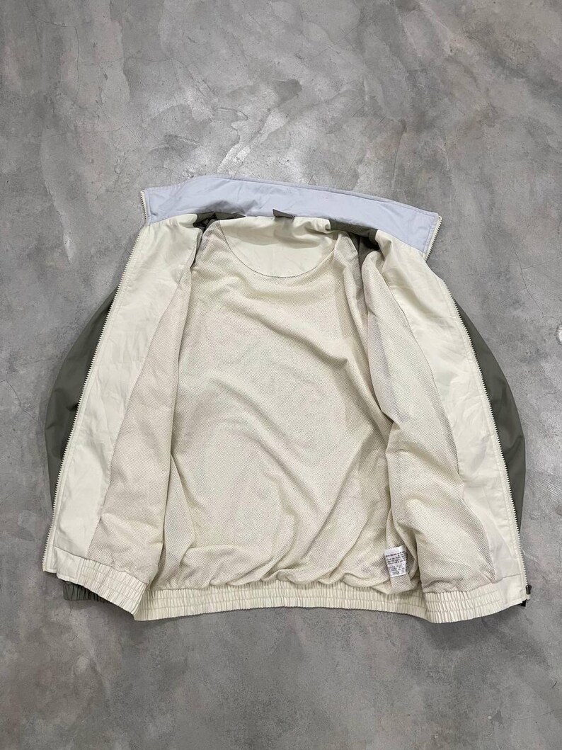 Peut inclure: Veste vert clair et cr&egrave;me avec un col bleu clair. La veste est ouverte, r&eacute;v&eacute;lant une doublure int&eacute;rieure cr&egrave;me. La veste a un ourlet et des poignets c&ocirc;tel&eacute;s. La veste est faite d'une mati&egrave;re l&eacute;g&egrave;re.