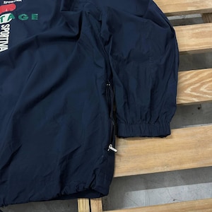 May include: A dark navy blue long-sleeve windbreaker jacket featuring a side zipper closure and elastic cuffs. The front displays partial white and green text that reads SPORTIVA and VINTAGE, along with a red graphic element near the top neckline.