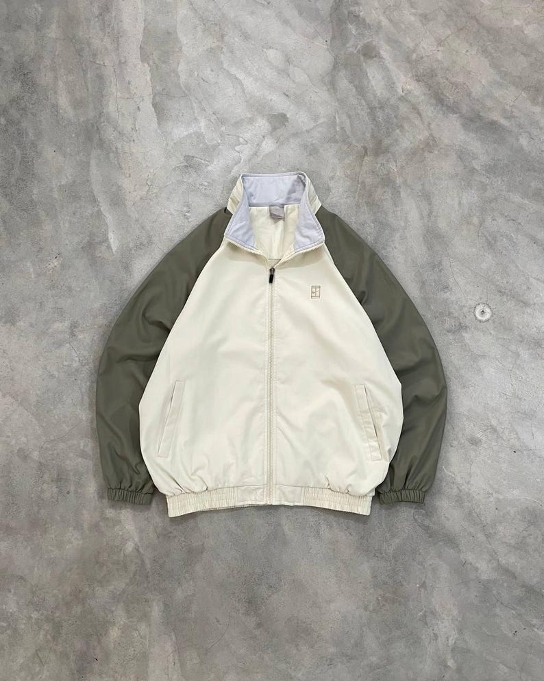 Peut inclure: Veste zipp&eacute;e cr&egrave;me avec des manches vert olive et un col gris clair. La veste pr&eacute;sente un petit logo sur la poitrine et deux poches avant. La veste a des poignets et un ourlet &eacute;lastiques.