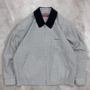 Peut inclure: Veste à fermeture éclair complète avec col noir et motif à carreaux gris et blanc. La veste a deux poches avant et un petit logo sur la poitrine. Fabriquée dans un matériau léger, elle est idéale pour le printemps.