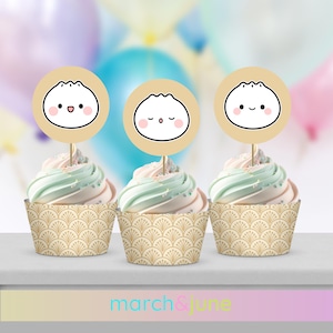 Puede incluir: Tres envoltorios para cupcakes con un patrón dorado y blanco. Cada cupcake tiene un glaseado blanco y verde y una pegatina redonda beige con una cara de dibujos animados en un palillo.