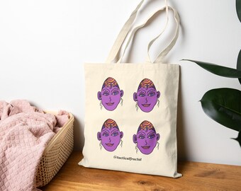 Puede incluir: Bolso tote de lona color crema con cuatro ilustraciones de caras moradas con cintas para la cabeza naranjas y amarillas. Las caras tienen ojos azules y están sonriendo. El texto "@tacticalfractal" está impreso debajo. El bolso tiene dos asas beige.