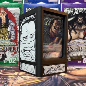 May include: Black card display case with a card featuring the character Crocodile. The case has a black frame with white graphic art on the sides and the word "Crocodile" on the front. Other One Piece card game boxes are in the background.