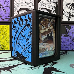 May include: A black 3D-printed deck box featuring a blue side panel with a relief illustration of a character. The front display window holds a trading card depicting Marshall D. Teach with the text 5000 visible in the upper right corner.