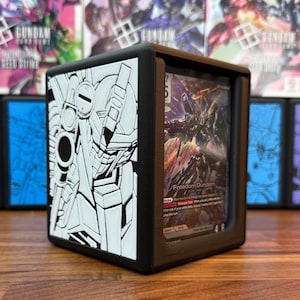May include: Black card case with a white embossed Gundam design on one side. The case holds a trading card with a Freedom Gundam illustration. Other card cases are visible in the background.