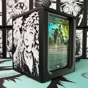 May include: A black plastic trading card display case featuring a side panel with a black and white illustration of a person with textured hair. The front window holds a Killian, Decisive Mentor card with green and blue magical energy effects.