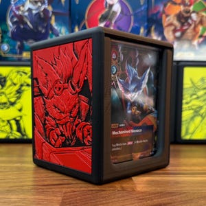 May include: A black card case with a red embossed design on one side and a card visible on the other. The card features a blue and white creature with the text "Mechanized Menace".