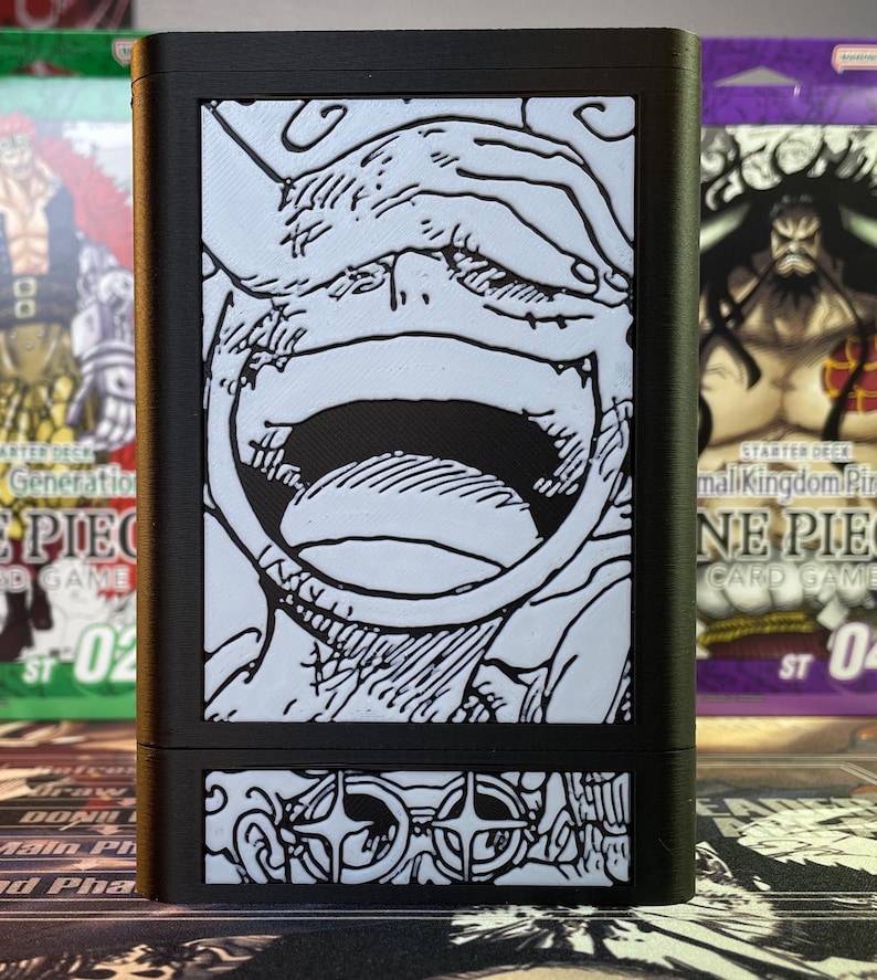 May include: Black card game deck box with a white and black illustration of a character's face with a large open mouth. The bottom of the box has a white and black illustration of a pair of glasses.