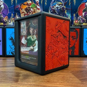 May include: Black card storage box with a red embossed design on the side. The box has a clear front panel displaying a card with the text "Bounty Hunter". Other boxes are visible in the background.