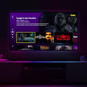 Puede incluir: Una pantalla de televisión muestra una interfaz de servicio de streaming con el título "Caught in the Crossfire". Otros títulos de películas visibles incluyen "Titans", "Batman" y "Back to the Future". El televisor está encima de un mueble oscuro con iluminación ambiental.