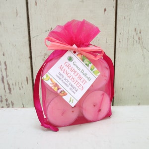 May include: A set of four pink grapefruit and mangosteen scented soy candles in a pink organza bag. The candles are hand-poured and vegan. The label reads "Green Daffodil Grapefruit Mangosteen 100% Soy Candle Hand Poured Vegan."