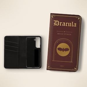 May include: A dark red wallet-style phone case featuring the gold-printed title Dracula by Bram Stoker, the year 1897, and a bat silhouette inside a circle. The interior is black with three card slots and a clear plastic phone holder.