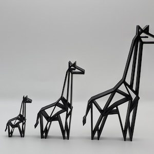 May include: Three black origami giraffes of different sizes. The largest giraffe is standing on the right, the medium-sized giraffe is in the middle, and the smallest giraffe is on the left.