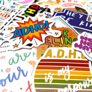Könnte beinhalten: Eine Sammlung bunter Aufkleber mit verschiedenen Designs und Sprüchen, darunter "ADHD!" und "A.D.H. ist meine Superkraft".