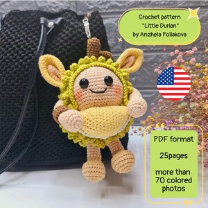 May include: A handmade crochet durian fruit charm with a smiling face, yellow and green details, and a keychain attachment. The text on the image says "Crochet pattern 'Little Durian' by Anzhela Poliakova".