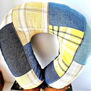 May include: A patchwork travel pillow in a U-shape, featuring denim, yellow plaid, and gray fabric sections. The pillow is designed for neck support and comfort, with a central opening. The color palette includes blue, yellow, and gray.