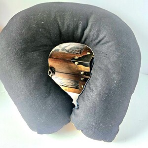May include: A black travel pillow with a decorative wooden chest design in the center. The pillow is U-shaped and made of soft fabric. The chest design features brown wood, metal accents, and a leopard print.