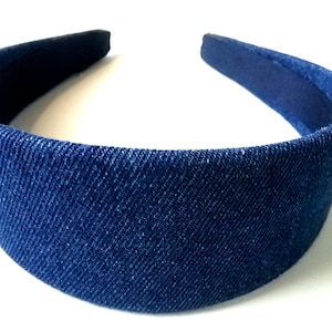 May include: A blue denim headband for hair. The headband is made of a soft, stretchy fabric.