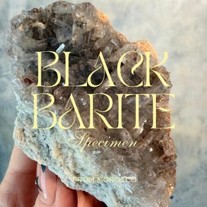 May include: A Black Barite specimen from Morocco. The mineral features a crystalline structure with a mix of clear, gray, and brown hues. The text "Black Barite Specimen" is displayed in a decorative font.