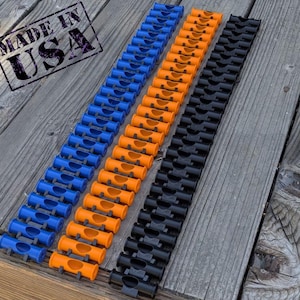 May include: A close-up of three rows of plastic connectors. The connectors are in three colors: black, orange, and blue. The connectors are arranged in a line on a wooden surface. The text "Made in USA" is visible in the top left corner of the image.