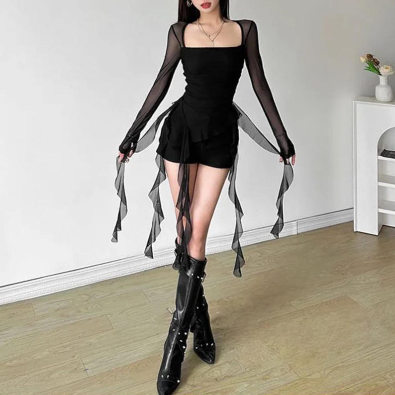 Women's Asymmetrical Mesh Tops | Long Sleeve Patchwork Shirt | Streetwear Y2k Chic Fashion

A fitted long sleeve top with cascading ribbon-like drapes extending at the sides, worn with wide-leg jeans. The piece has a structured upper silhouette and flowing layered accents for a dramatic, fashion-forward look.