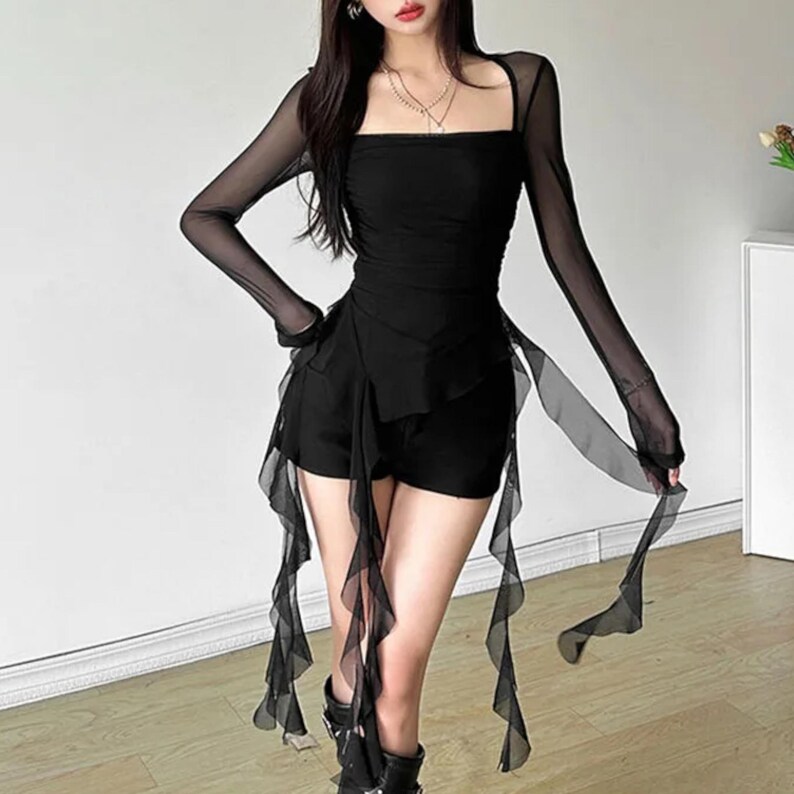 Women's Asymmetrical Mesh Tops | Long Sleeve Patchwork Shirt | Streetwear Y2k Chic Fashion

A fitted long sleeve top with cascading ribbon-like drapes extending at the sides, worn with wide-leg jeans. The piece has a structured upper silhouette and flowing layered accents for a dramatic, fashion-forward look.