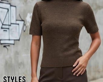 May include: A dark brown short-sleeved sweater featuring a mock neck collar and ribbed detailing on the sleeves and hem. The garment is paired with dark brown trousers. The text STYLES BY LITA is visible in the lower left corner of the image.
