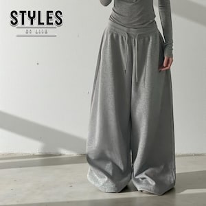 May include: A person wearing a gray long-sleeved top and wide-leg sweatpants. The sweatpants have a drawstring waist. The text "STYLES BY LITA" is in the upper left corner.