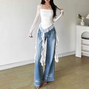 Women's Asymmetrical Mesh Tops | Long Sleeve Patchwork Shirt | Streetwear Y2k Chic Fashion

A fitted long sleeve top with cascading ribbon-like drapes extending at the sides, worn with wide-leg jeans. The piece has a structured upper silhouette and flowing layered accents for a dramatic, fashion-forward look.