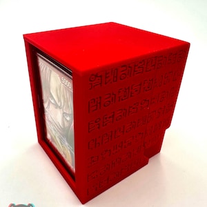 May include: A bright red card storage box with etched designs. The box is rectangular with a slot to view the cards inside. The text "5000" is visible on a card. The logo "Print and Chill 3D" is at the bottom.