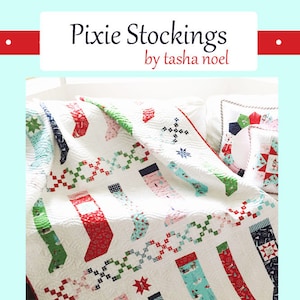 May include: A white quilt with a Christmas stocking pattern in red, blue, green, and pink fabrics. The quilt is called "Pixie Stockings" by Tasha Noel and is numbered #507.