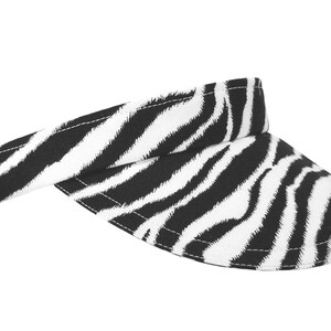 Puede incluir: Una visera de estampado de cebra en blanco y negro.