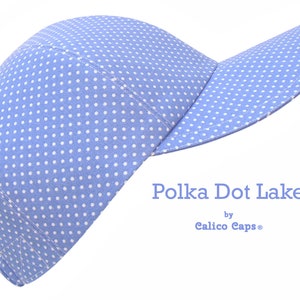 K&ouml;nnte beinhalten: Eine hellblaue Baseballkappe mit wei&szlig;en Punkten. Die Kappe hat einen gebogenen Schirm und ist aus einem weichen, bequemen Stoff gefertigt. Der Text "Polka Dot Lake by Calico Caps&reg;" ist auf der Vorderseite der Kappe aufgedruckt.