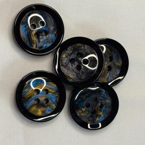 Könnte beinhalten: Sechs schwarze Knöpfe mit einem Wirbelmuster in Blautönen, Gold und Schwarz. Die Knöpfe haben jeweils vier Löcher.