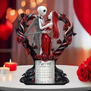 Puede incluir: Una figura decorativa con Jack Skellington y Sally de The Nightmare Before Christmas, abraz&aacute;ndose dentro de un marco en forma de coraz&oacute;n adornado con rosas rojas. La base incluye un calendario para enero de 2025, con la palabra "Married" y los nombres "Michael & Emma".