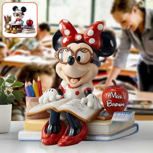 May include: A Minnie Mouse figurine wearing glasses and a red polka dot bow, seated on books and reading. She wears a white dress with red accents and red shoes. An apple with "Mrs. Brown" is next to her, along with pencils and a calculator.