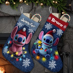 Könnte beinhalten: Zwei Weihnachtsstrümpfe mit Stitch-Figuren, einer rosa und einer blauen, die jeweils einen Weihnachtsmannhut tragen und mit Lichterketten umwickelt sind. Die Strümpfe sind jeansblau mit Schneeflockenmustern und personalisierten Namen.