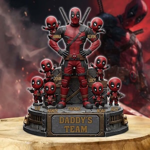 Può includere: Una statuetta di Deadpool rossa e nera con la scritta "DADDY'S TEAM" sulla base. La statuetta raffigura Deadpool circondato da statuette più piccole di Deadpool con nomi come Anna, Kevin, John, Lucy, Leo, Nancy, Thomas, Noah e Alex.