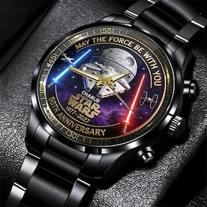 May include: Black watch with a Star Wars theme. The watch face features the Death Star, Millennium Falcon, and lightsabers. Text includes "May the Force Be With You" and "50th Anniversary 1977-2027".