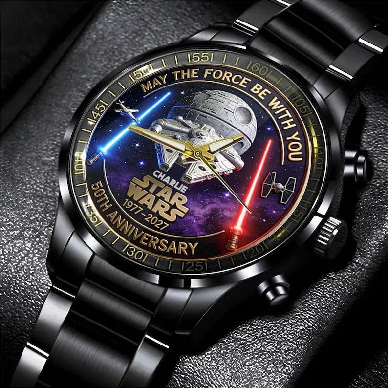 May include: Black watch with a Star Wars theme. The watch face features the Death Star, Millennium Falcon, and lightsabers. Text includes "May the Force Be With You" and "50th Anniversary 1977-2027".