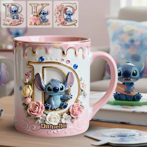 Può includere: Una tazza in ceramica bianca e rosa con un personaggio Stitch 3D e dettagli floreali. La tazza ha un manico e un bordo rosa, con la lettera "D" in oro. Il nome "Daniella" è scritto sulla tazza.