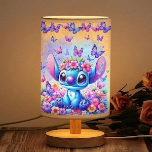 May include: A blue and purple personalised nightlight featuring a cartoon character wearing a flower crown and the name "Sophia" on the base. The nightlight is surrounded by butterflies and flowers.