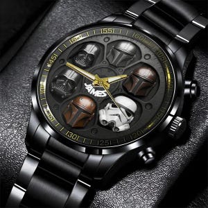 May include: Black wristwatch with a dark face featuring embossed character helmets. The watch has gold hands and a black metal band. The word "JAMES" is printed on the watch face.