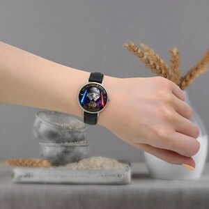 May include: A black leather strap watch with a silver case. The watch face features a Star Wars design with the text "MAY THE FORCE BE WITH YOU" and "STAR WARS 50TH ANNIVERSARY".