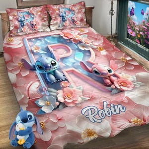 Peut inclure: Une courtepointe rose et blanche avec une grande lettre R au centre. La lettre est faite de cristaux bleus et blancs. Deux personnages Stitch sont de chaque côté de la lettre. La courtepointe a un motif floral et le nom Robin est écrit en lettres bleues en bas.